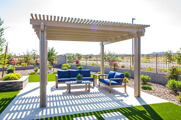 Small pergola in a large backyard area over a patio with some furniture